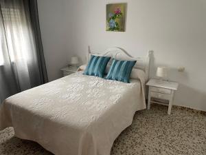 a bedroom with a white bed with blue pillows at Apartamento Antonia muy cerca de la playa in Bolonia