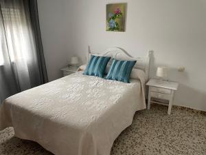 Un dormitorio con una cama blanca con almohadas azules. en Apartamento Antonia muy cerca de la playa, en Bolonia