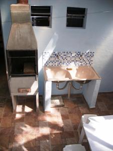 cocina con chimenea, fregadero y fogones en Casinhas na Praia do Julião em Ilhabela SP, en Ilhabela
