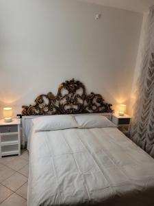 a bedroom with a white bed with a ornate headboard at Casa BuIIo in Chioggia