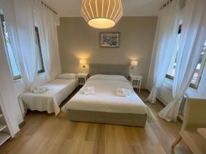 a bedroom with two beds and a chandelier and windows at B&B Casa al Vicolo 2 in Taormina