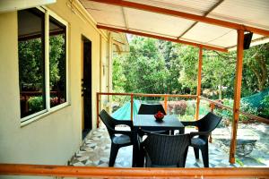 un patio con tavolo e sedie su un balcone di MERIDIAN AC VILLA - Besides Valley View & Strawberry Farms a Mahabaleshwar