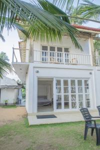 Casa blanca con ventanas grandes y balcón. en Kodi Beach Home, en Galle
