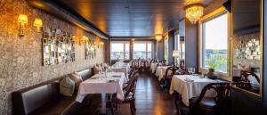 a dining room with white tables and chairs and windows at Hotel Victoria in Skellefteå