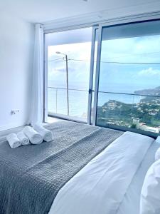 een slaapkamer met een bed met een groot raam bij Villa Cassolino in Ribeira Brava