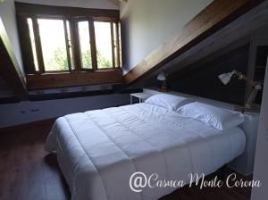 um quarto com uma grande cama branca e 2 janelas em Casa con encanto en La Hayuela, situada a 5 min de Comillas em Udias
