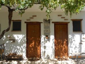 um edifício com duas portas de madeira e uma árvore em S'Imbragu Farm B&B em Tortolì