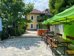 patio ze stołami i krzesłami oraz zielonym parasolem w obiekcie Balaton7 Apartmanház - Badacsonytomaj Centrum w mieście Badacsonytomaj