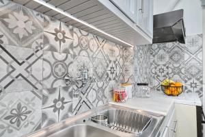 a kitchen with a sink and a tile wall at Vanilla guesthouse in Skopelos Town