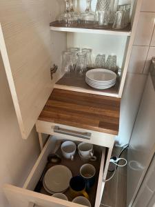a cupboard with plates and dishes in a kitchen at Csikós Apartman in Gyenesdiás