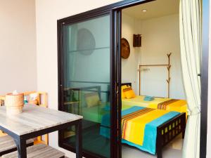 Zimmer mit einem Bett, einem Tisch und einer Glastür in der Unterkunft Mae-Sa-Riang Home in Mae Sariang