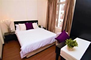 a bedroom with a white bed with purple pillows at Melaka Town Area Top 1 Family Lovers Water Themepark Suites By GGM in Melaka +32 photos