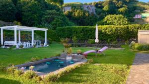 a swimming pool in a yard with a slide at Casa do Priolo - Villaverde Azores in Feteiras +12 photos