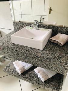 a bathroom counter with a sink and towels on it at Pousada Central in Urubici