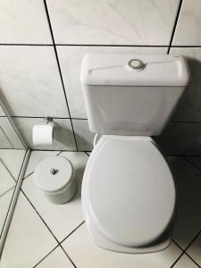 a white toilet in a bathroom with a roll of toilet paper at Pousada Central in Urubici