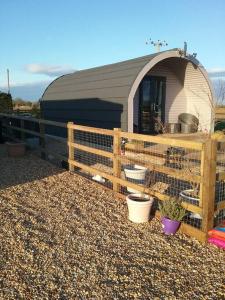 a fence with plants in front of a building at Heated Supersize Glamping Pod with ensuite bathroom, Wilburton, Nr Ely, Cambs in Wilburton