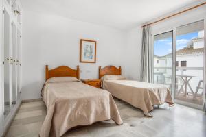 two beds in a room with a window at Duquesa Harbour Club Aparthotel in Manilva