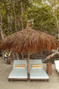 twee bedden onder een rieten parasol op het strand bij Fragata Island House in Cartagena