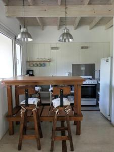 una cocina con una gran barra de madera con taburetes en Casa de Moras, en Tandil