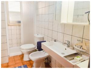 a white bathroom with a toilet and a sink at Hostel Vela Vega in Butera