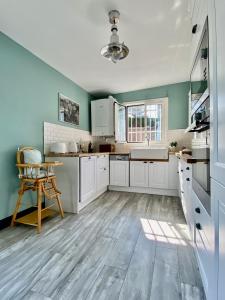 a kitchen with white cabinets and a wooden floor at Villa Sophie in Trouville-sur-Mer