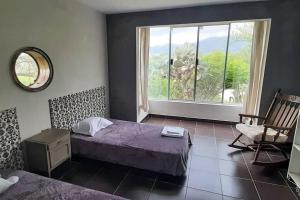 1 dormitorio con cama, ventana y silla en Residencia en Tomatitas, en Tarija