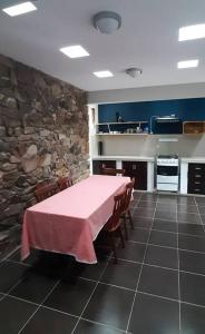 cocina con mesa y pared de piedra en Residencia en Tomatitas en Tarija