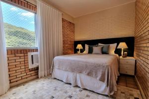 Un dormitorio con una cama grande y una ventana en Aguas de Cachoeira, en Florianópolis