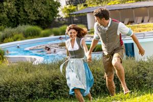 a man and a woman walking by a swimming pool at Best Western Aparthotel Birnbachhöhe in Bad Birnbach