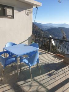 una mesa azul y sillas en un balcón con vistas en The Kumaon Retreat, en Nainital