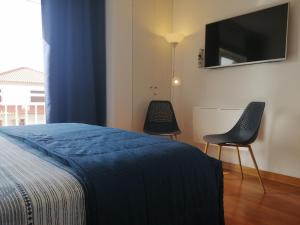 1 dormitorio con 1 cama, 2 sillas y TV de pantalla plana en RoyalHeronHouse, en Viana do Castelo