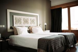 um quarto com uma grande cama branca e uma janela em Quinta do Paço Hotel em Vila Real