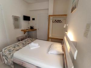 a small bedroom with a white bed with two pillows at Peaceful Bay in Megas Yialos-Nites