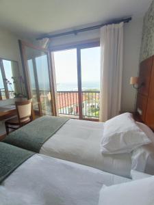 a hotel room with two beds and a large window at Hotel A Raiña in Oia