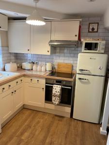 a kitchen with white cabinets and a white refrigerator at Bell Cottage right in the heart of Bridgnorth in Bridgnorth