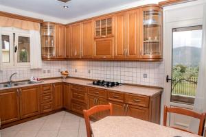 a kitchen with wooden cabinets and a sink and a window at Laki Villa with pool and jacuzzi in Ágios Geórgios