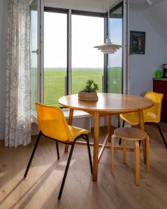 comedor con mesa, sillas y ventana en Ollediek, en Houwerzijl