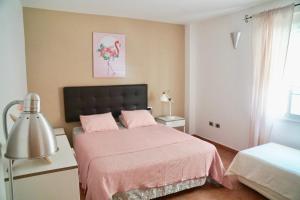 a bedroom with a bed with pink sheets and a lamp at Family and Friends , Familienapartment Playa de San Juan in Guía de Isora