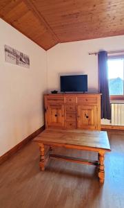 um banco de madeira num quarto com uma televisão num armário em Le Chalet de Poche - Gite 2 étoiles - 5 pers em Habère-Poche