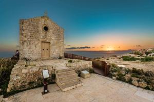 a church on a hill with the sunset in the background at Ta' Palal in Dingli