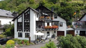 a white and black building with flowers in the windows at Ferienwohnung Im Bachtal in Pommern