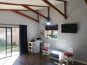 a room with a desk and a tv and chairs at Thatchers Guest Rooms in Welkom