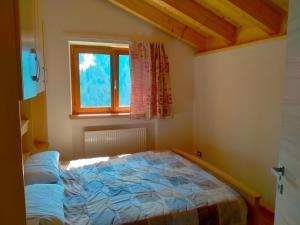 a bedroom with a bed in a room with a window at Pelmo Mountain Lodge in Selva di Cadore