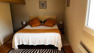 a small bedroom with a bed with orange pillows at Le Cocon Gite in Saint-Trojan-les-Bains