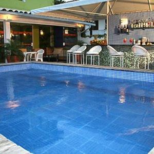 een groot blauw zwembad met stoelen en een bar bij Departamento Dos reis in Búzios