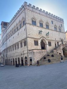 un gran edificio de piedra con gente de pie delante de él en Artist apartment centro storico, en Perugia