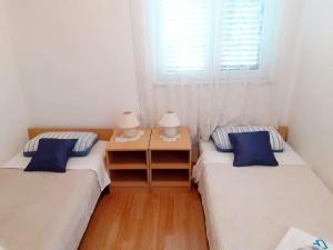2 Einzelbetten in einem Zimmer mit Fenster in der Unterkunft Apartmani Brkljača 2 -Ive in Biograd na Moru