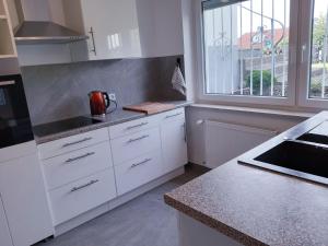 eine Küche mit weißen Schränken und einem Fenster in der Unterkunft Traumwohnung in Feldrandlage in Rod am Berg + 1 Foto