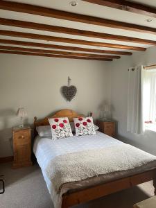 Schlafzimmer mit einem Bett mit roten und weißen Kissen in der Unterkunft Farriers Cottage in Grantham