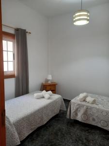 een slaapkamer met 2 bedden, een raam en een kroonluchter bij El Girasol in Arinaga